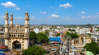 The Charminar's four minarets rising above Hyderabad's old city with the surrounding bazaar and skyline.