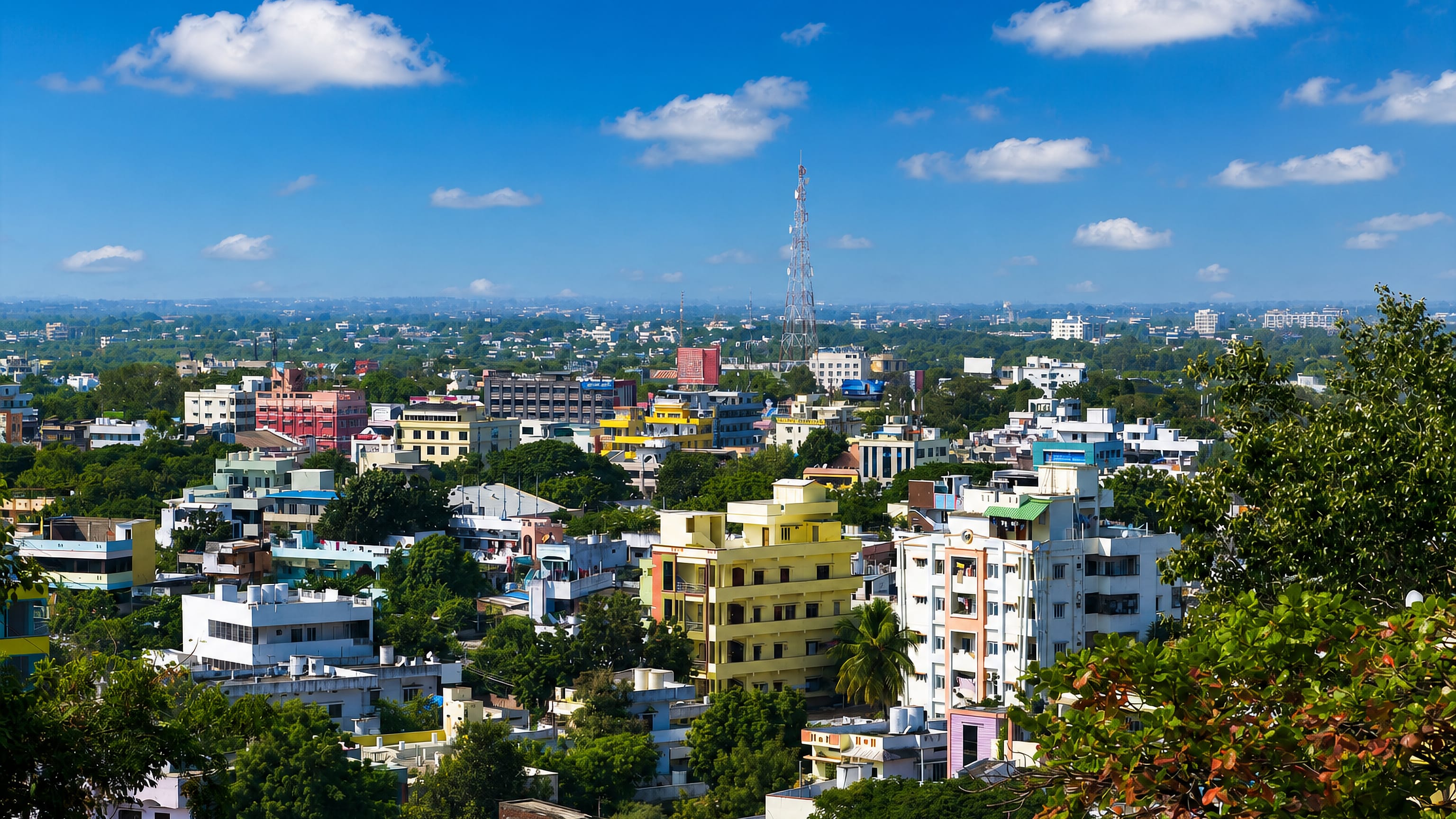 Khammam's dense pastel low-rise rooftops below a lattice communications mast on the Telangana plain