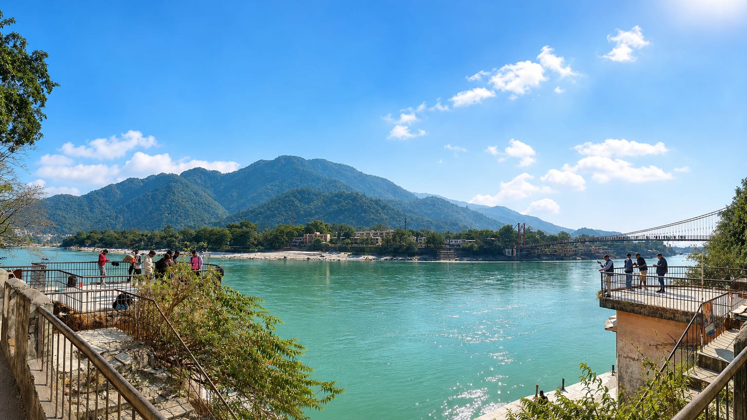 The turquoise Ganges at Rishikesh with a suspension bridge and forested hills
