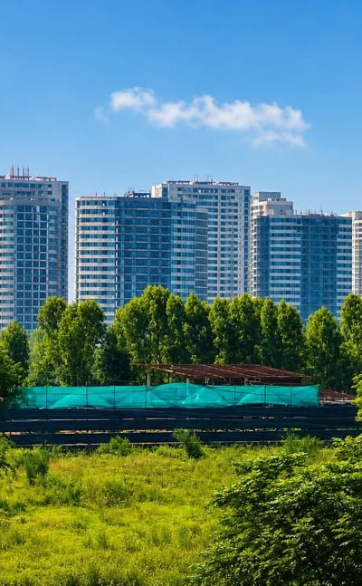 Modern residential high-rise towers behind green trees and open parkland in Chandigarh, India.