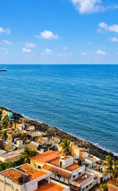Puducherry's rocky seafront with colorful houses, palms and the old pier along the Bay of Bengal