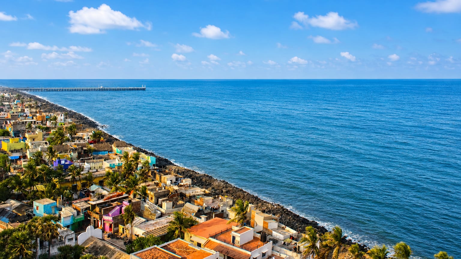 Puducherry's rocky seafront with colorful houses, palms and the old pier along the Bay of Bengal