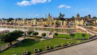 Ayodhya's Ram ki Paidi ghats and temple-crowned skyline along the Sarayu river under a blue daytime sky.