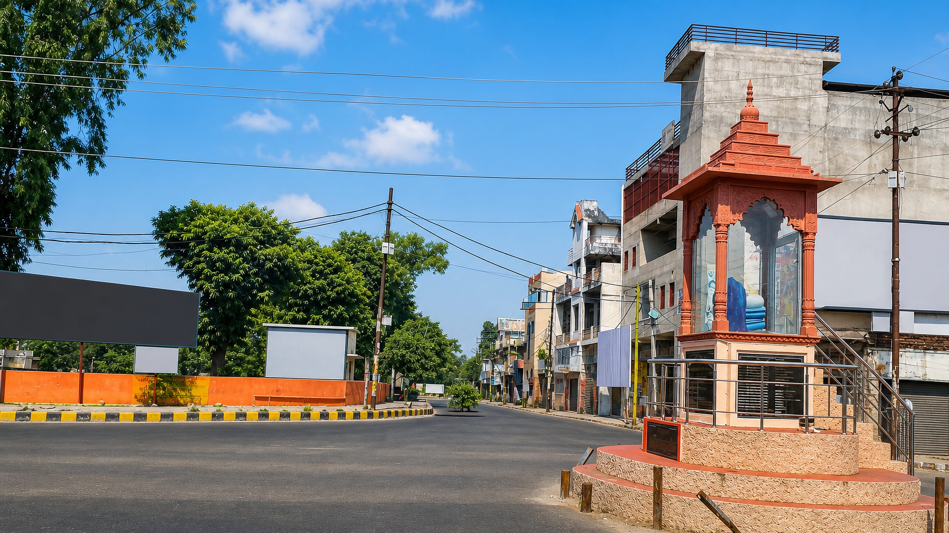 An ornate orange roadside shrine on a quiet street corner in Budaun, Uttar Pradesh, under a bright sky.