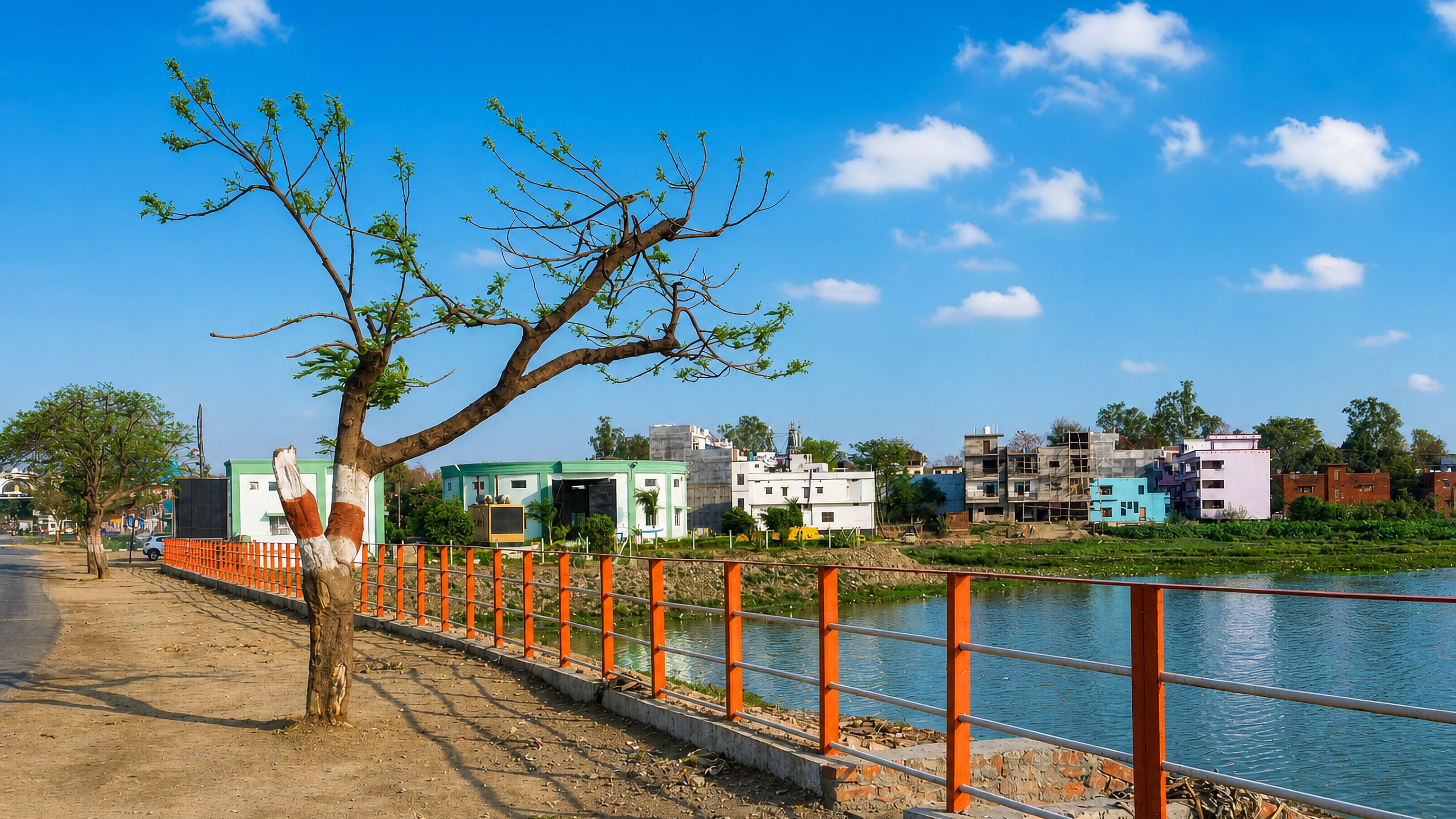 Railed lakeside promenade and low-rise houses across the water at Gorakhpur in Uttar Pradesh, India.