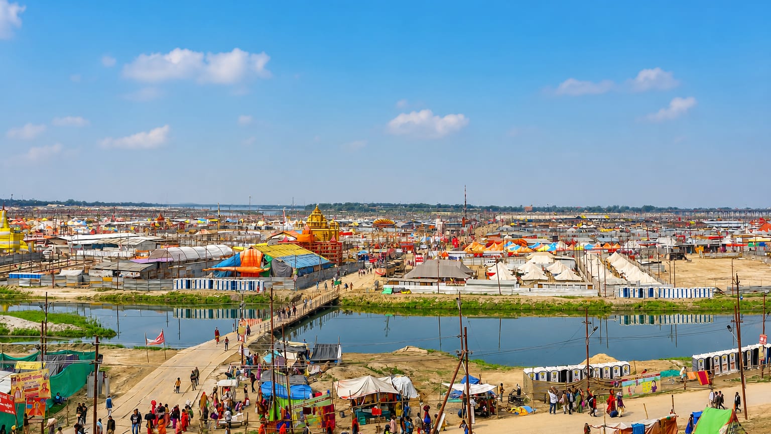 Vast riverside festival grounds at Prayagraj with colourful temples and tents lining the Ganges-Yamuna confluence
