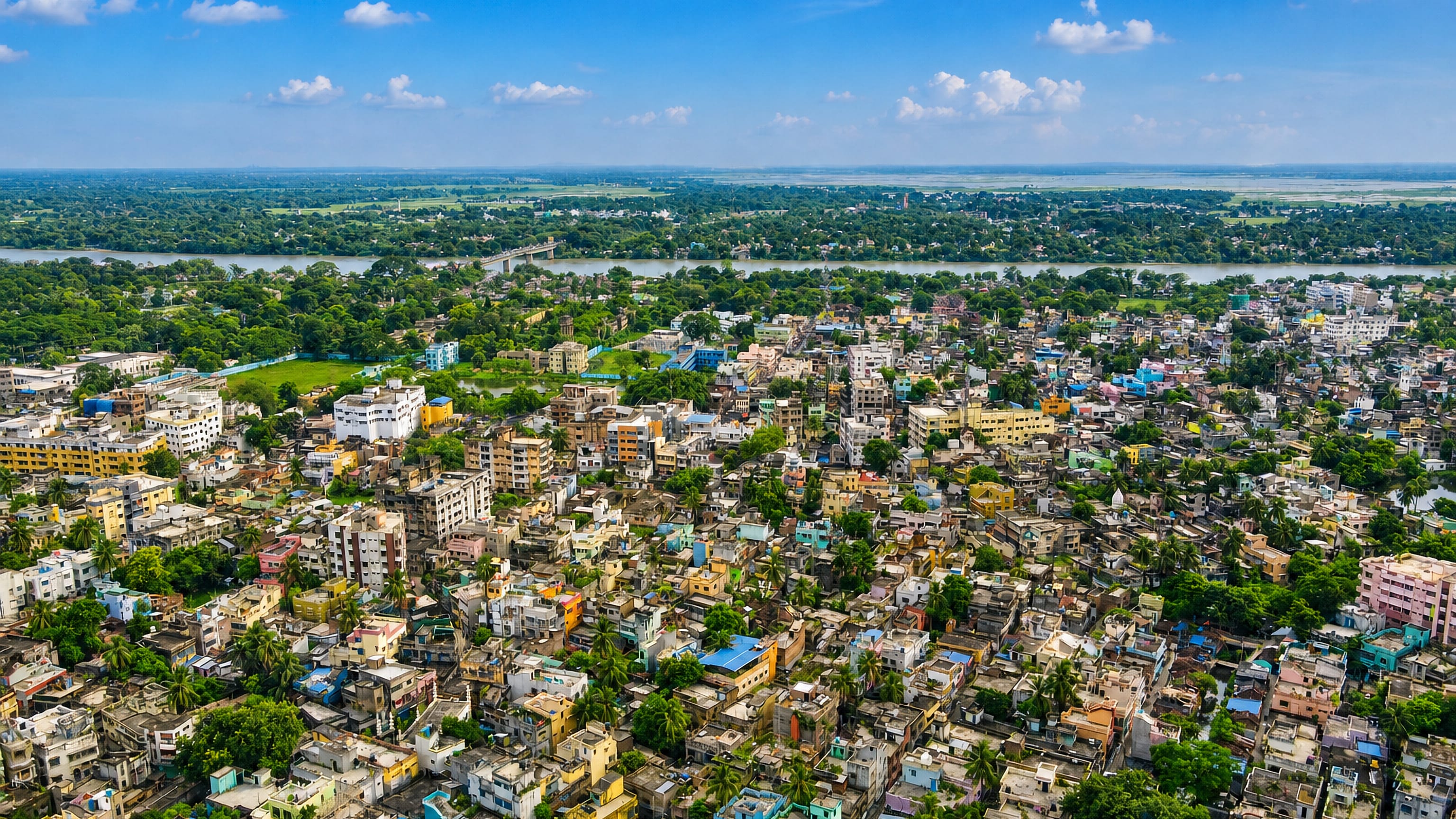 Aerial view of Baharampur, West Bengal, with dense colourful rooftops beside the Bhagirathi River and green plains.