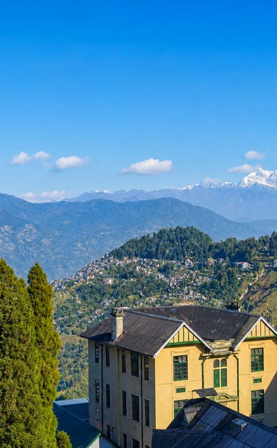 Darjeeling's ridgetop buildings with the snow-capped Kangchenjunga range beyond the Himalayan foothills.
