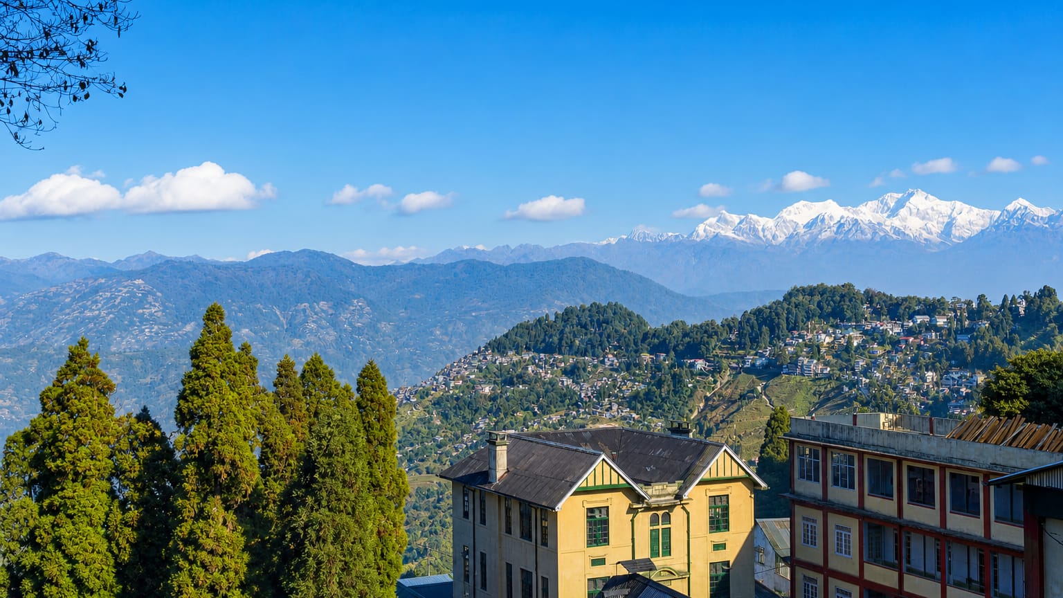 Darjeeling's ridgetop buildings with the snow-capped Kangchenjunga range beyond the Himalayan foothills.