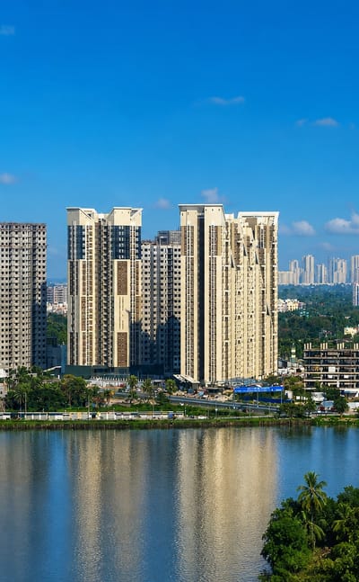 Modern high-rise apartment towers rising above a lakeside fringed with tropical greenery in Kolkata