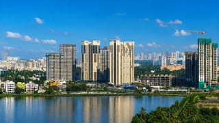 Modern high-rise apartment towers rising above a lakeside fringed with tropical greenery in Kolkata