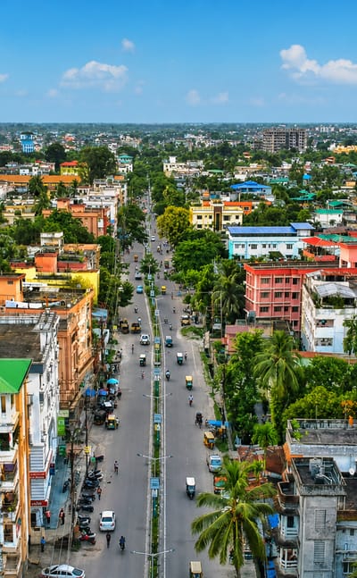 Aerial view of a Siliguri street lined with colourful buildings and palm trees