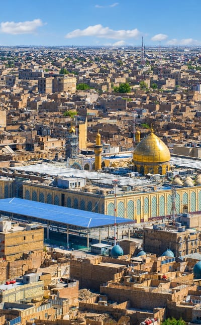 Aerial view of Najaf, Iraq, centred on the Imam Ali Shrine's golden dome and minarets amid the old city.