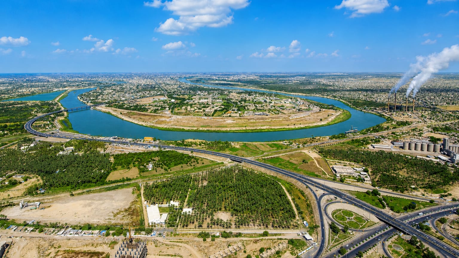 Aerial view of the Tigris river bend and highway interchanges past Dora district in Baghdad, with a power station on the horizon