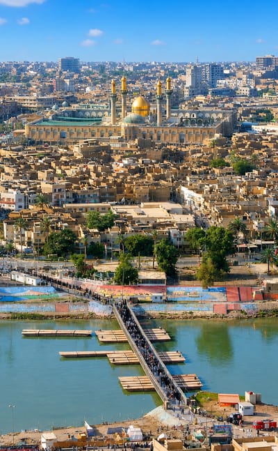 Golden domes and minarets of the Al-Kadhimiya Shrine rising over Baghdad's Kadhimiya district beside the Tigris