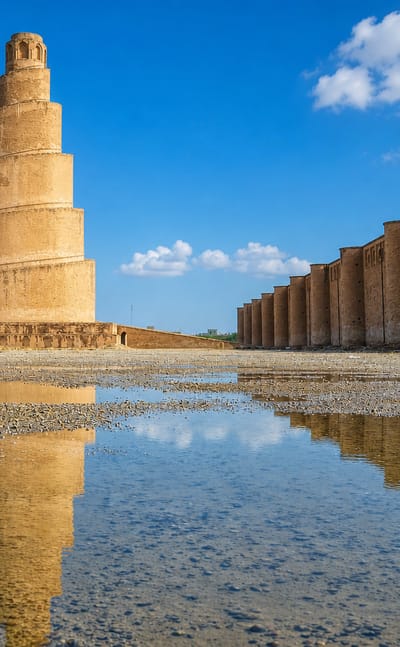 The Great Mosque of Samarra with its spiral Malwiya minaret and outer wall reflected in water, Iraq.