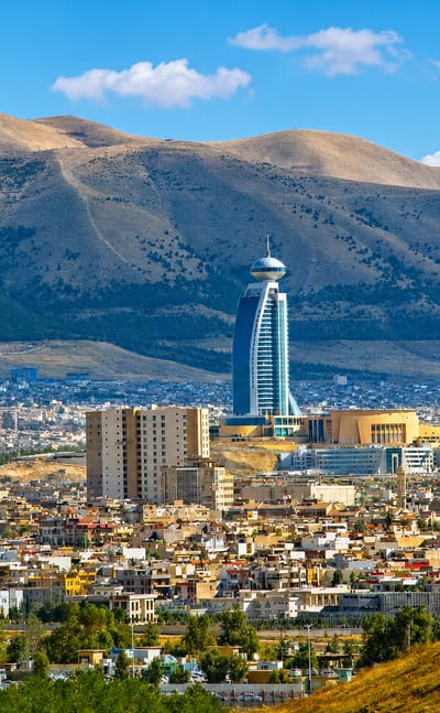 Sulaymaniyah spread below barren mountains, a tall bulbous-topped tower rising above the low-rise city.