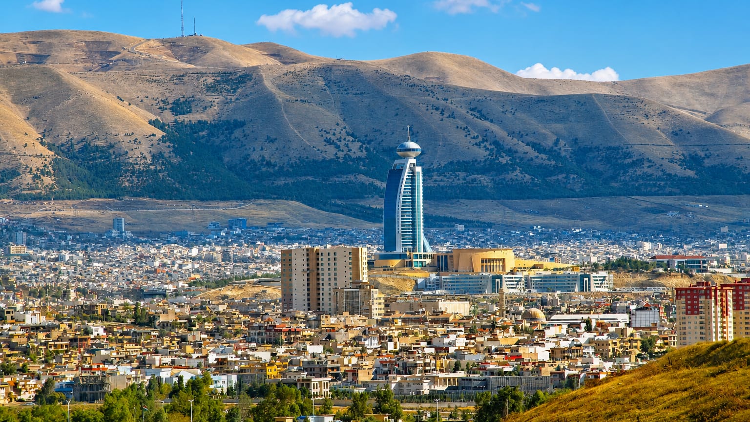 Sulaymaniyah spread below barren mountains, a tall bulbous-topped tower rising above the low-rise city.