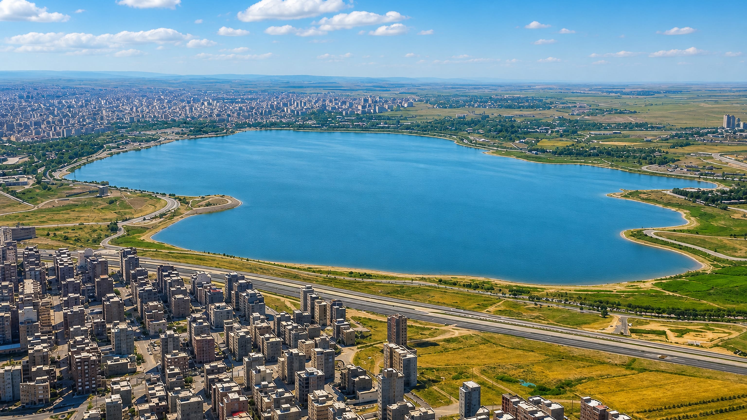Aerial view of Ardabil, Iran, with apartment blocks beside a large lake on the open plain.