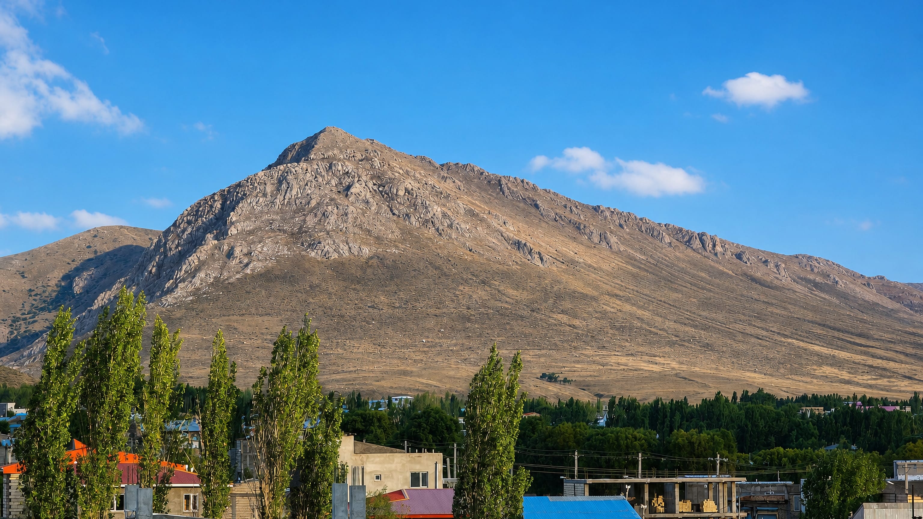 Rocky mountain rising above the low houses and poplars of Khalkhal in Iran's Ardabil province.