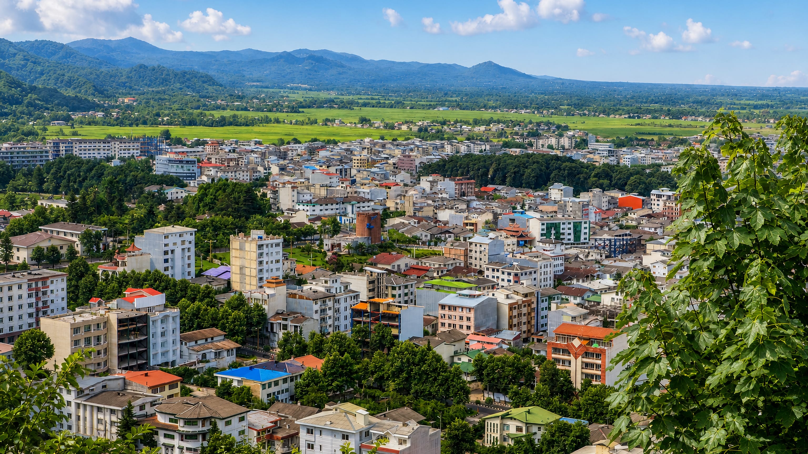Hillside panorama over Lahijan's colourful rooftops toward tea-covered plains and forested Alborz foothills in Gilan.
