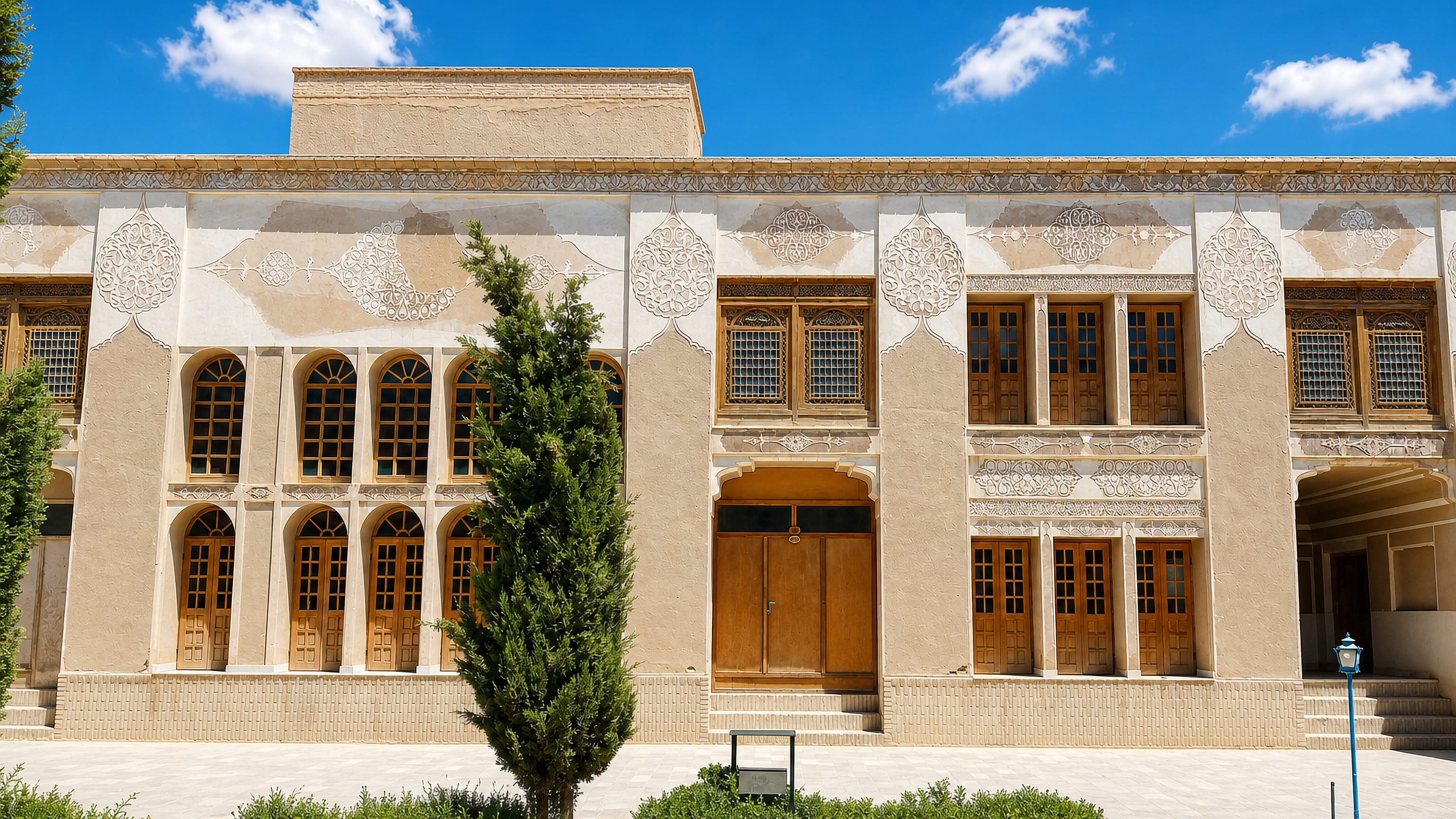 Traditional Persian courtyard house with carved stucco panels and wooden windows in Shahr-e Bābak, Iran.