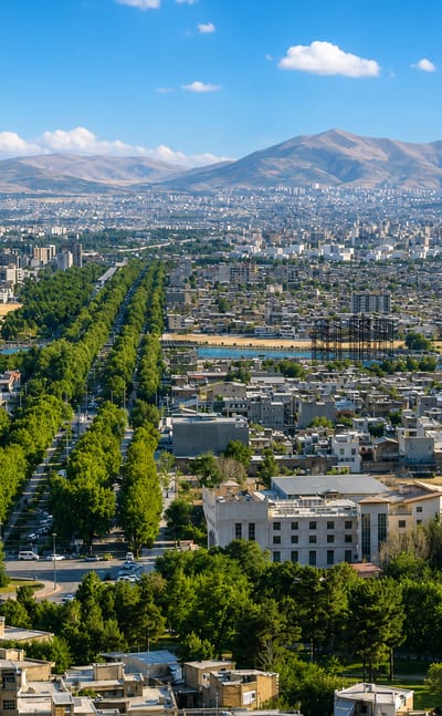 Aerial cityscape of Kermanshah with a tree-lined boulevard and mountains behind, Iran