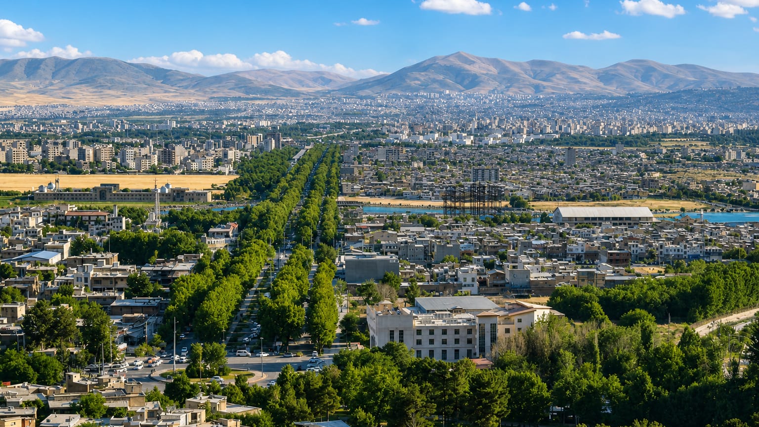 Aerial cityscape of Kermanshah with a tree-lined boulevard and mountains behind, Iran