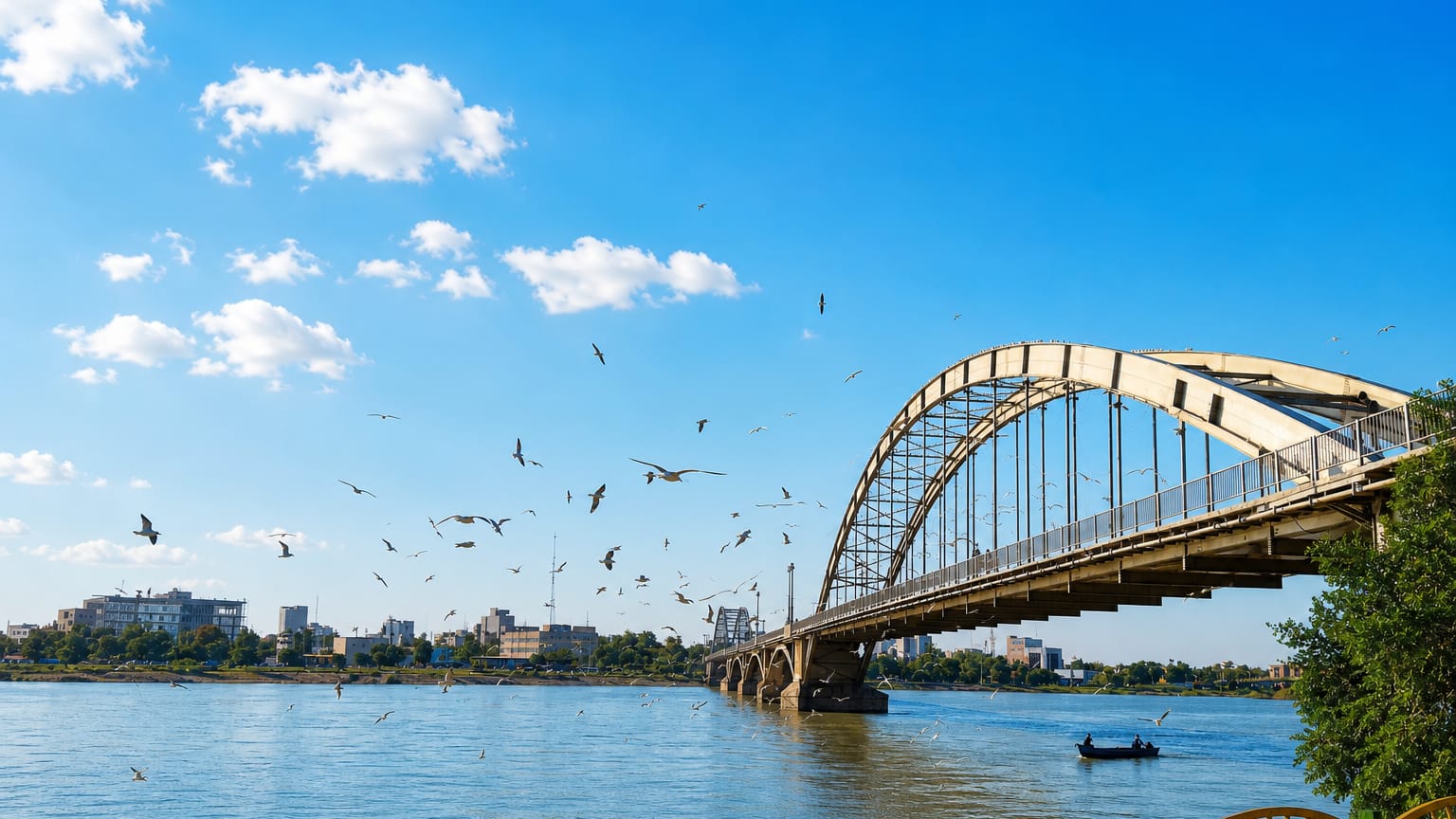 Ahvaz's white arched bridge over the Karun River with birds wheeling above the water.
