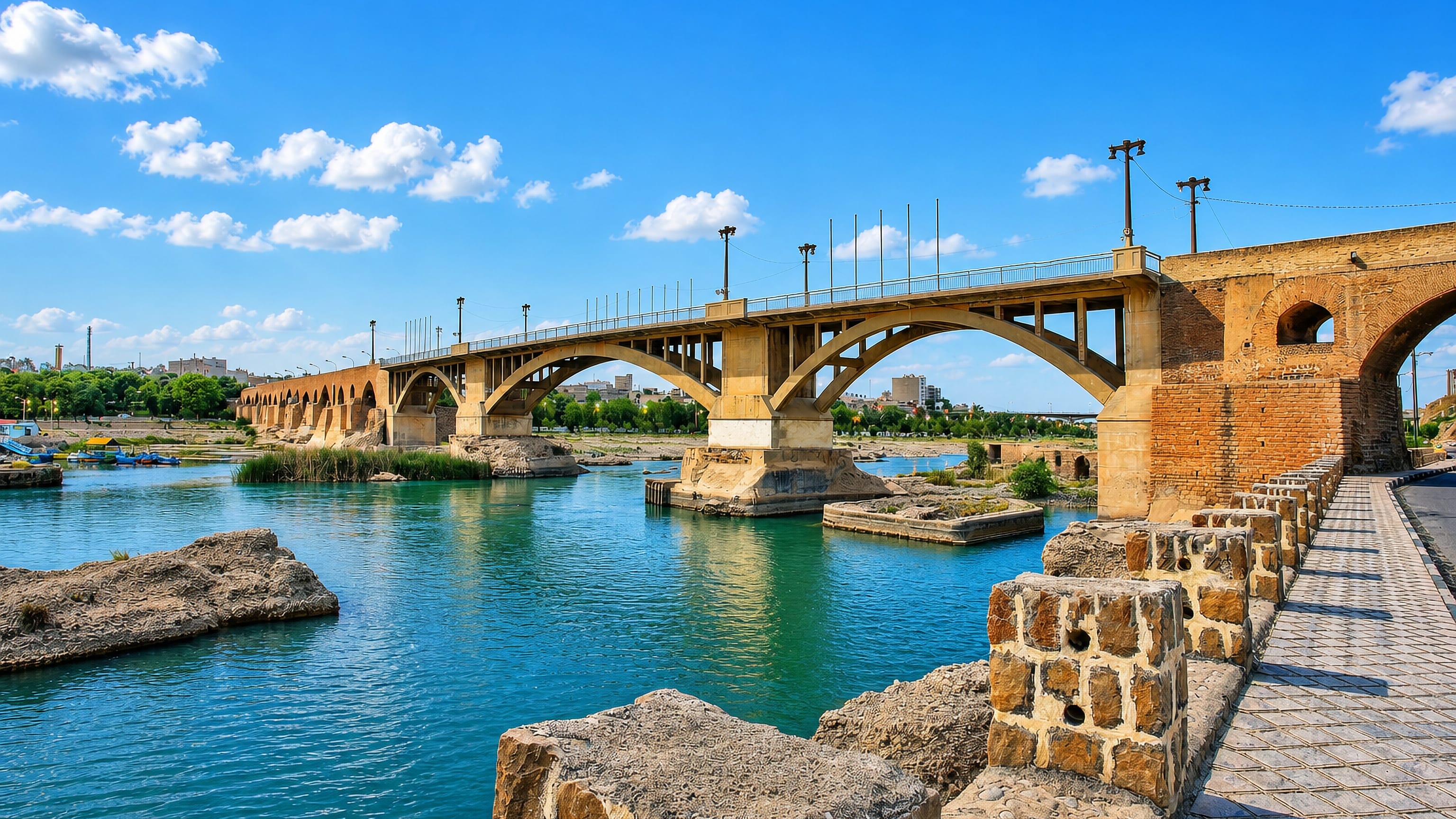 The historic brick bridge and modern arched span crossing the Dez River at Dezful, Iran.