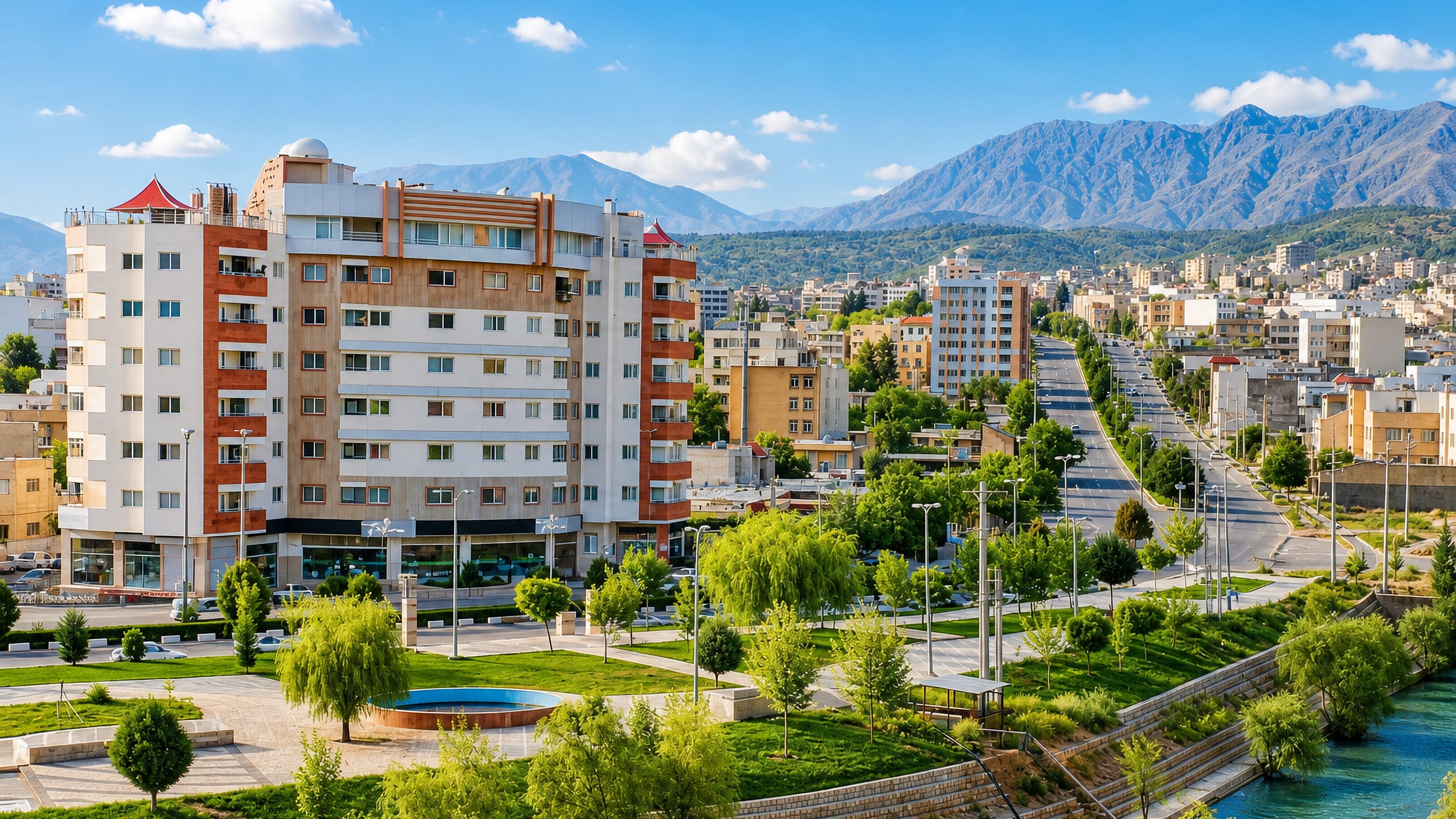 Mid-rise apartments, a riverside park and Zagros peaks framing Yasuj in southwestern Iran.