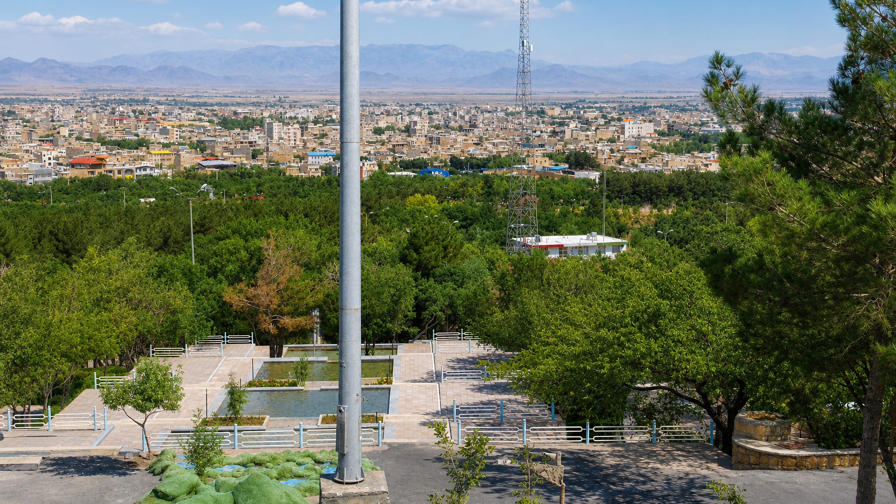 Hillside park terrace overlooking the low-rise town of Khomeyn and the plain and mountains beyond.