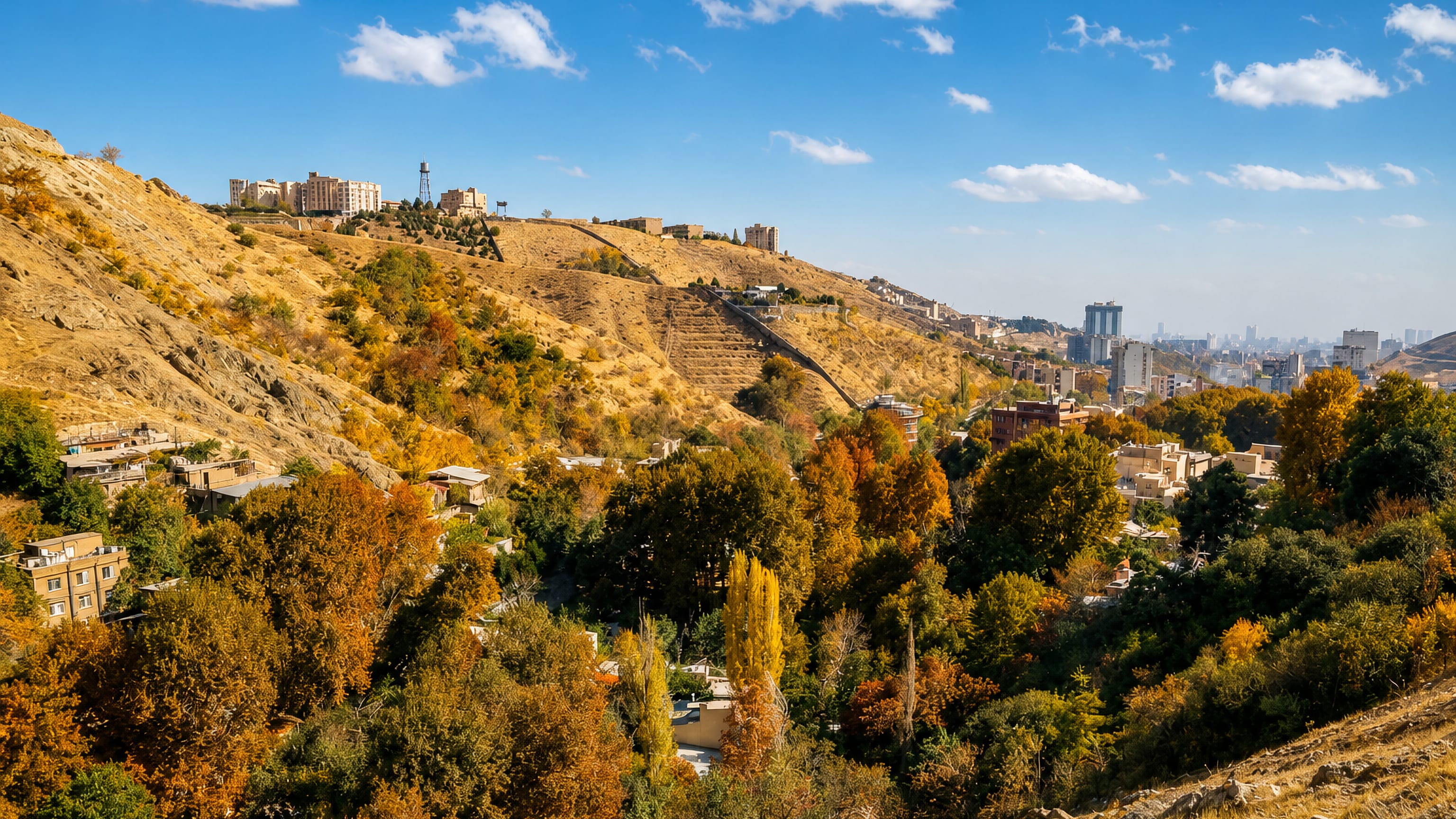 Autumn trees and hillside houses in Darakeh on the Alborz foothills above the distant Tehran skyline