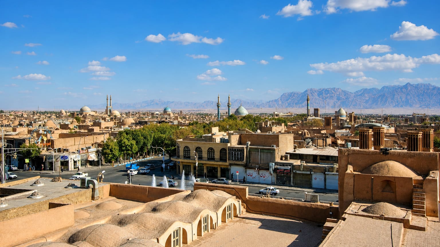 Rooftops, windcatchers, domes and minarets of the mudbrick old city of Yazd with mountains beyond.