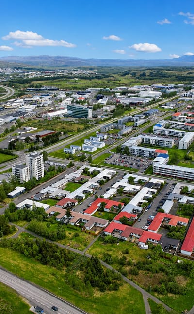 Aerial view of Árbær, a residential suburb of eastern Reykjavík, with colourful rooftops and distant mountains.