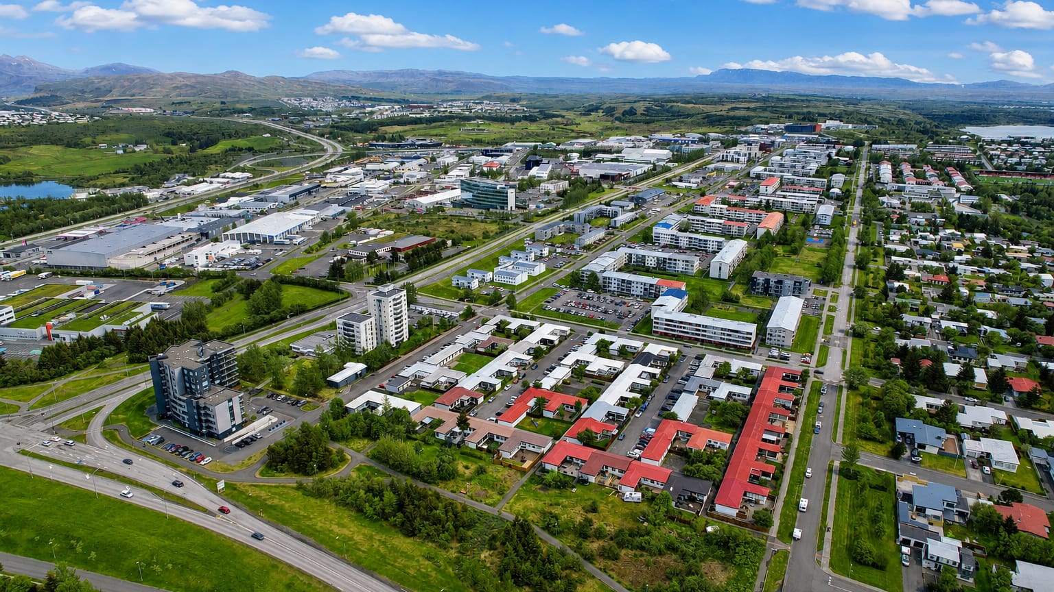 Aerial view of Árbær, a residential suburb of eastern Reykjavík, with colourful rooftops and distant mountains.