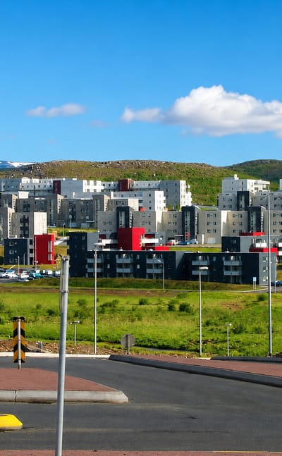 Modern apartment blocks of Grafarholt og Úlfarsárdalur rising on green hills below distant mountains in eastern Reykjavík.