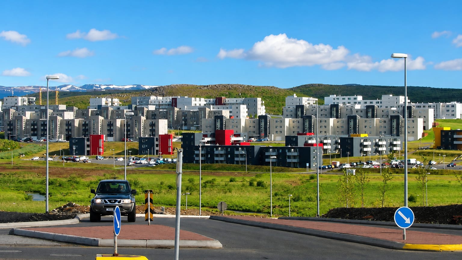 Modern apartment blocks of Grafarholt og Úlfarsárdalur rising on green hills below distant mountains in eastern Reykjavík.
