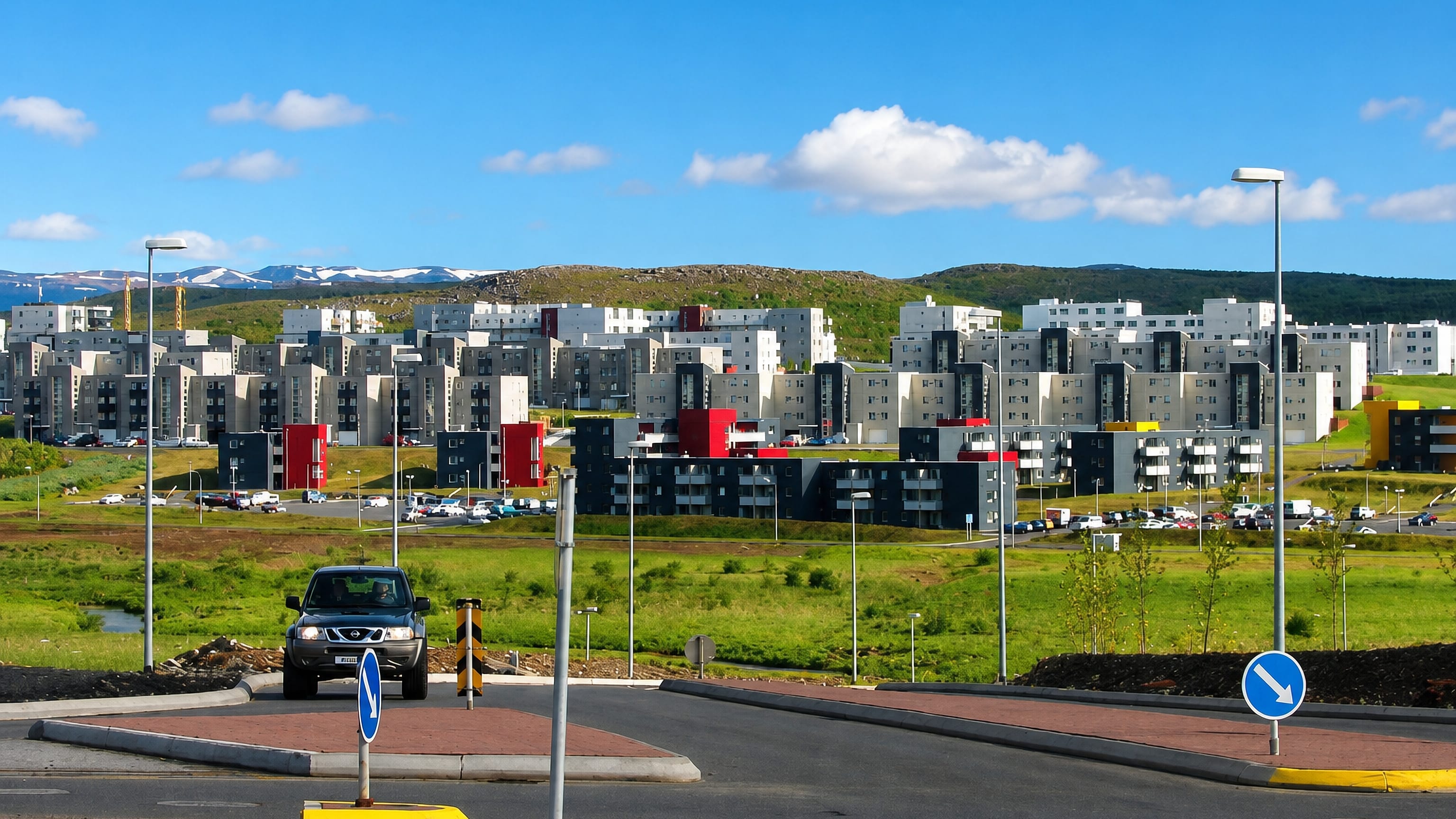 Modern apartment blocks of Grafarholt og Úlfarsárdalur rising on green hills below distant mountains in eastern Reykjavík.