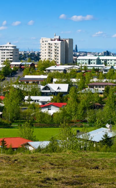 Low-rise houses with colourful roofs among green spaces and apartment blocks in Grafarvogur, a suburb of Reykjavík, Iceland.
