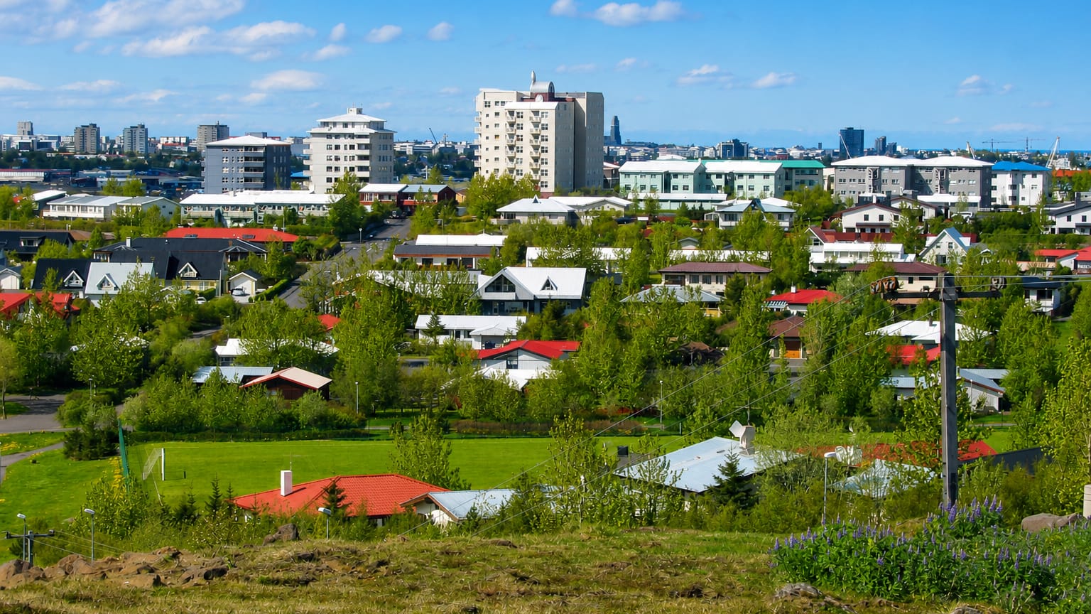 Low-rise houses with colourful roofs among green spaces and apartment blocks in Grafarvogur, a suburb of Reykjavík, Iceland.