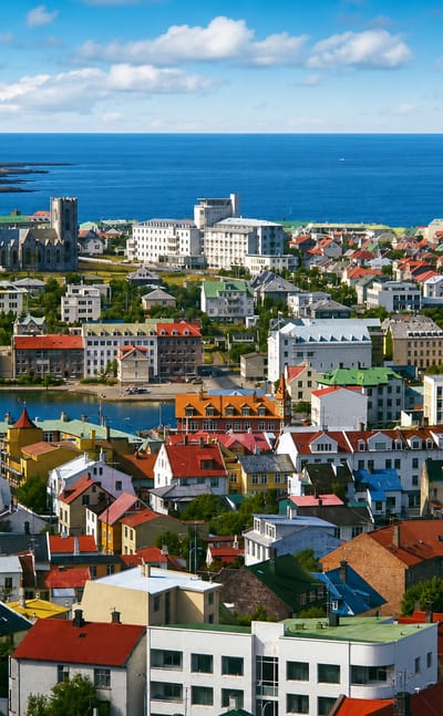 Elevated view across the colorful rooftops of Vesturbær in Reykjavík, toward the bay and the open Atlantic.