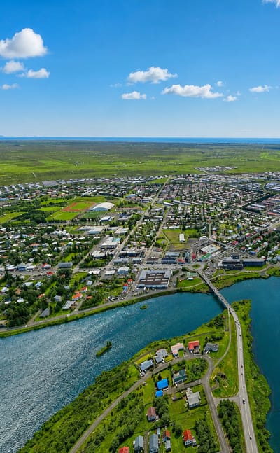 Aerial view of Selfoss, Iceland, a low-rise town along the wide Ölfusá river and bridge in South Iceland's green lowlands