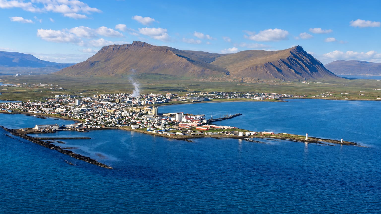 Aerial view of Akranes, Iceland, a peninsula town with a lighthouse beneath the twin-peaked Akrafjall mountain.