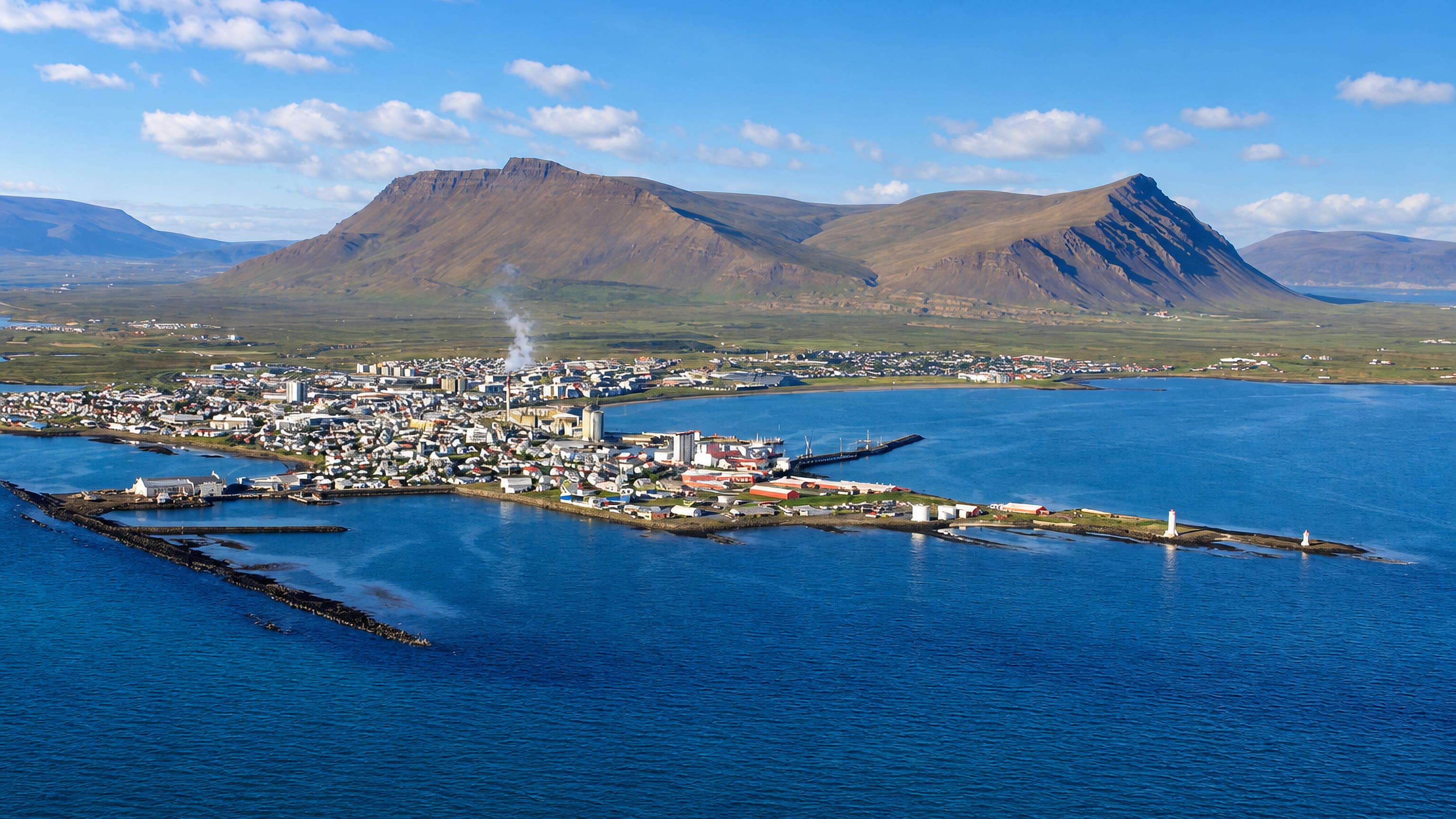 Aerial view of Akranes, Iceland, a peninsula town with a lighthouse beneath the twin-peaked Akrafjall mountain.