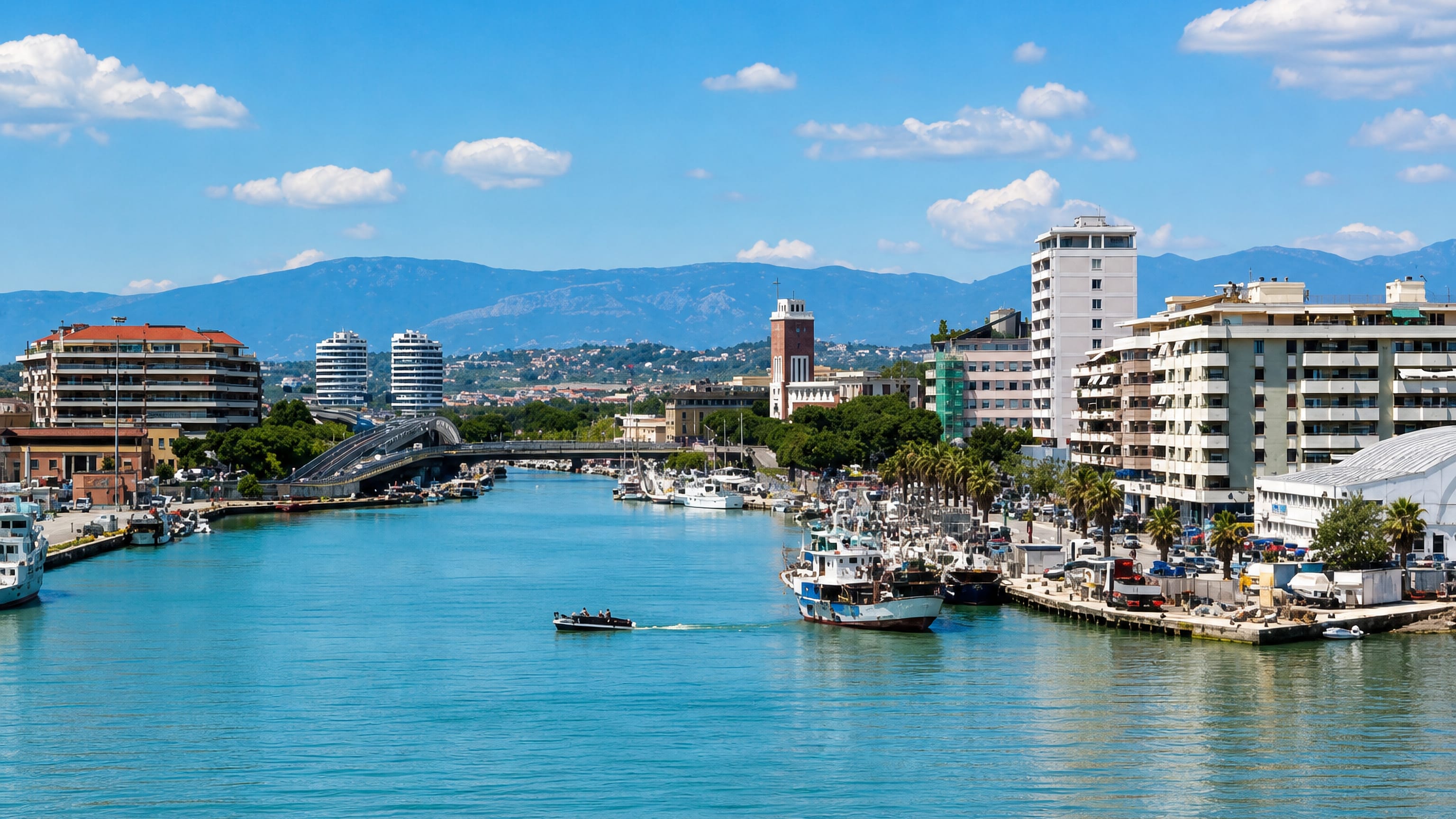 Fishing boats and waterfront apartment blocks along the Pescara river, with the Abruzzo mountains beyond.