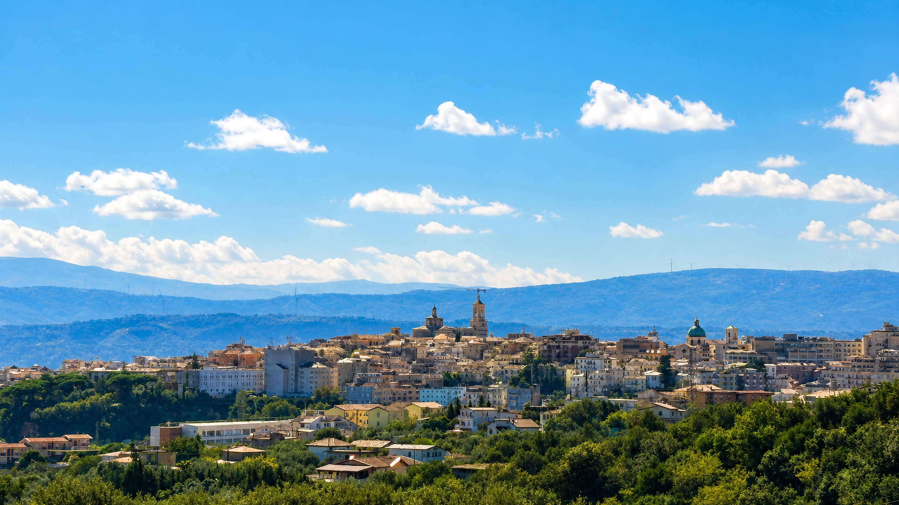 Catanzaro's hilltop old town, domes and bell towers rising above wooded ravines with Calabrian mountains behind