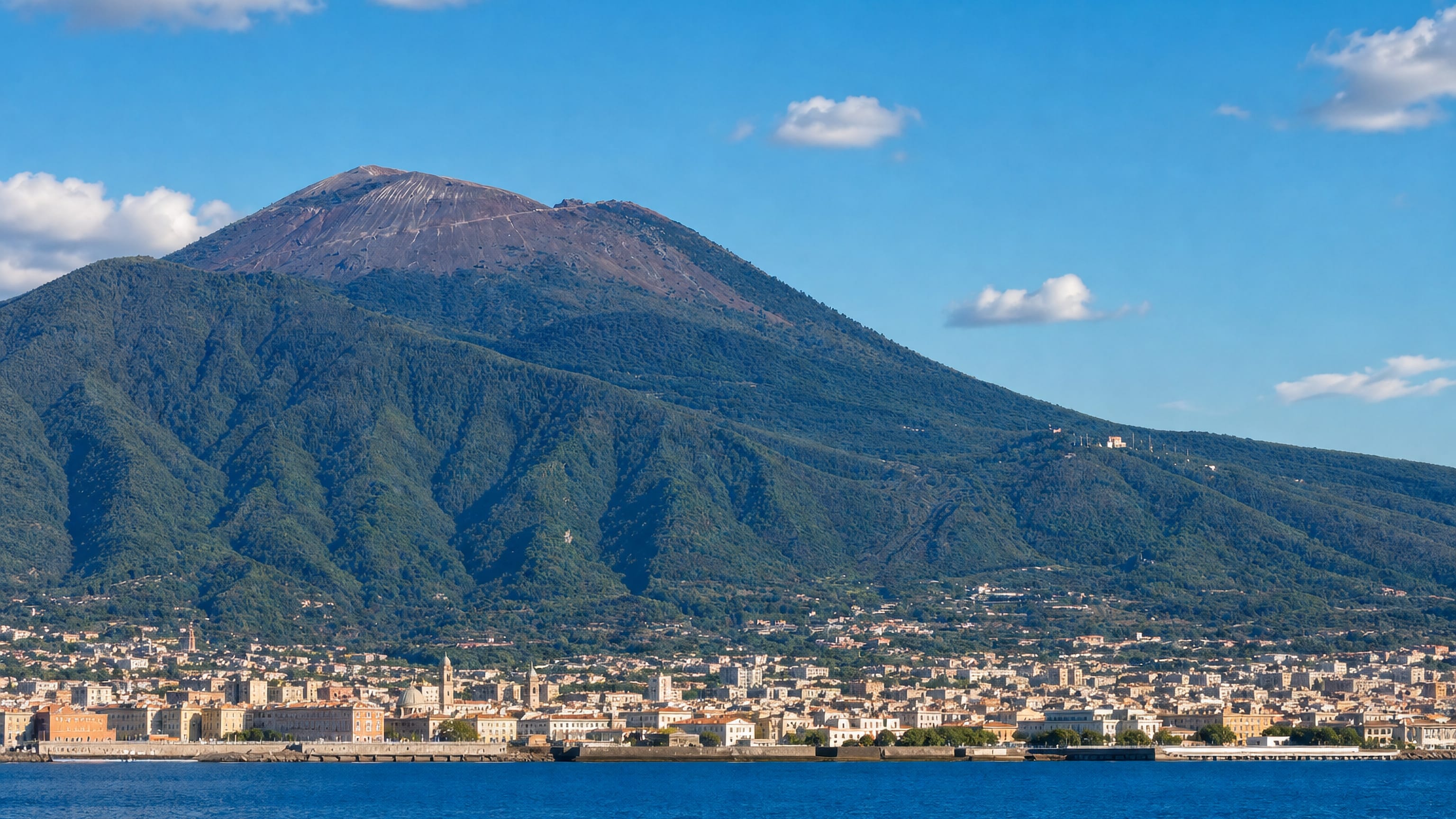 Ercolano on the Bay of Naples, its waterfront terraces spread below the wooded slopes and bare cone of Vesuvius.