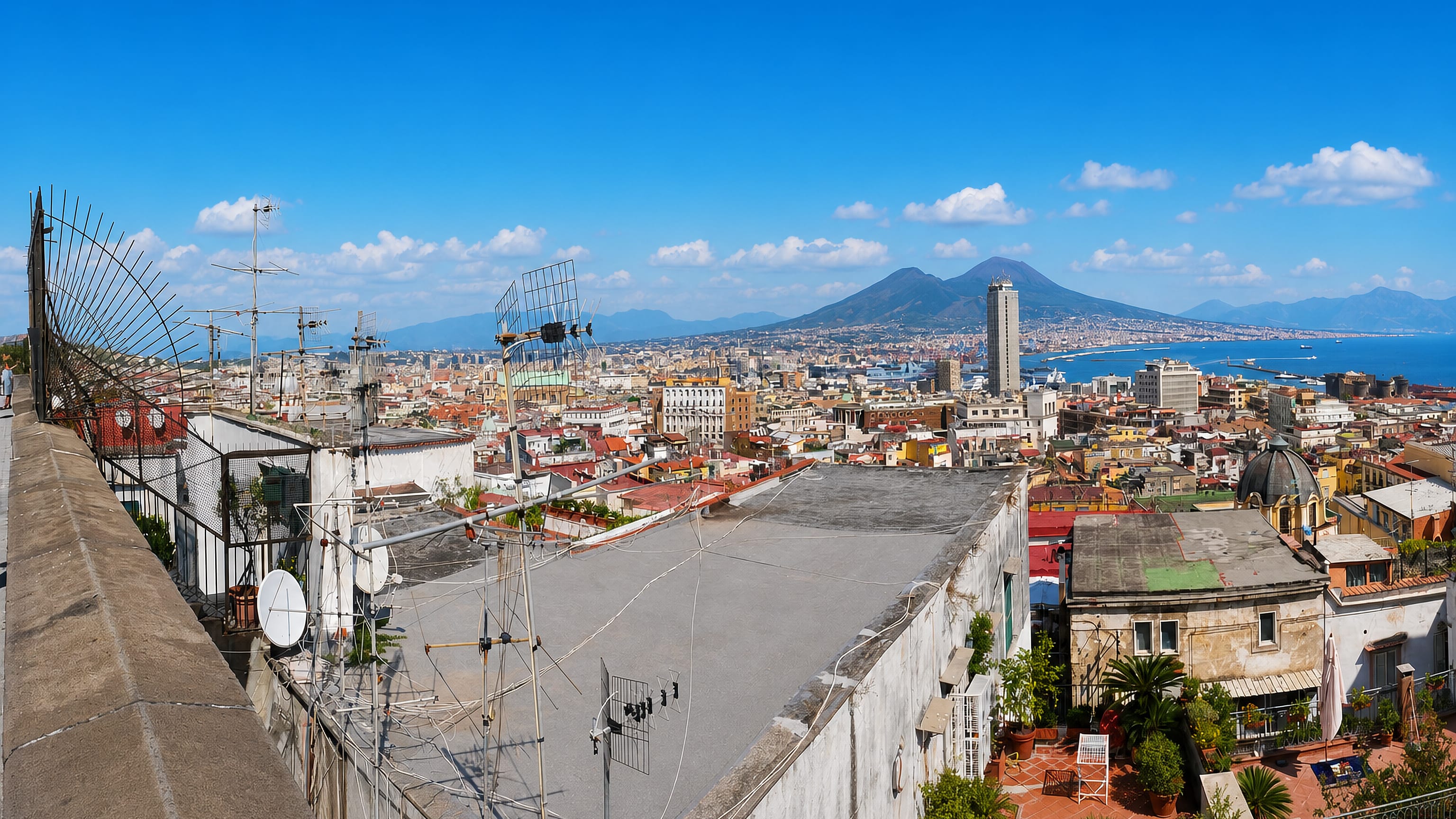 Rooftops of Montecalvario in Naples looking across the bay to Mount Vesuvius under a clear sky.