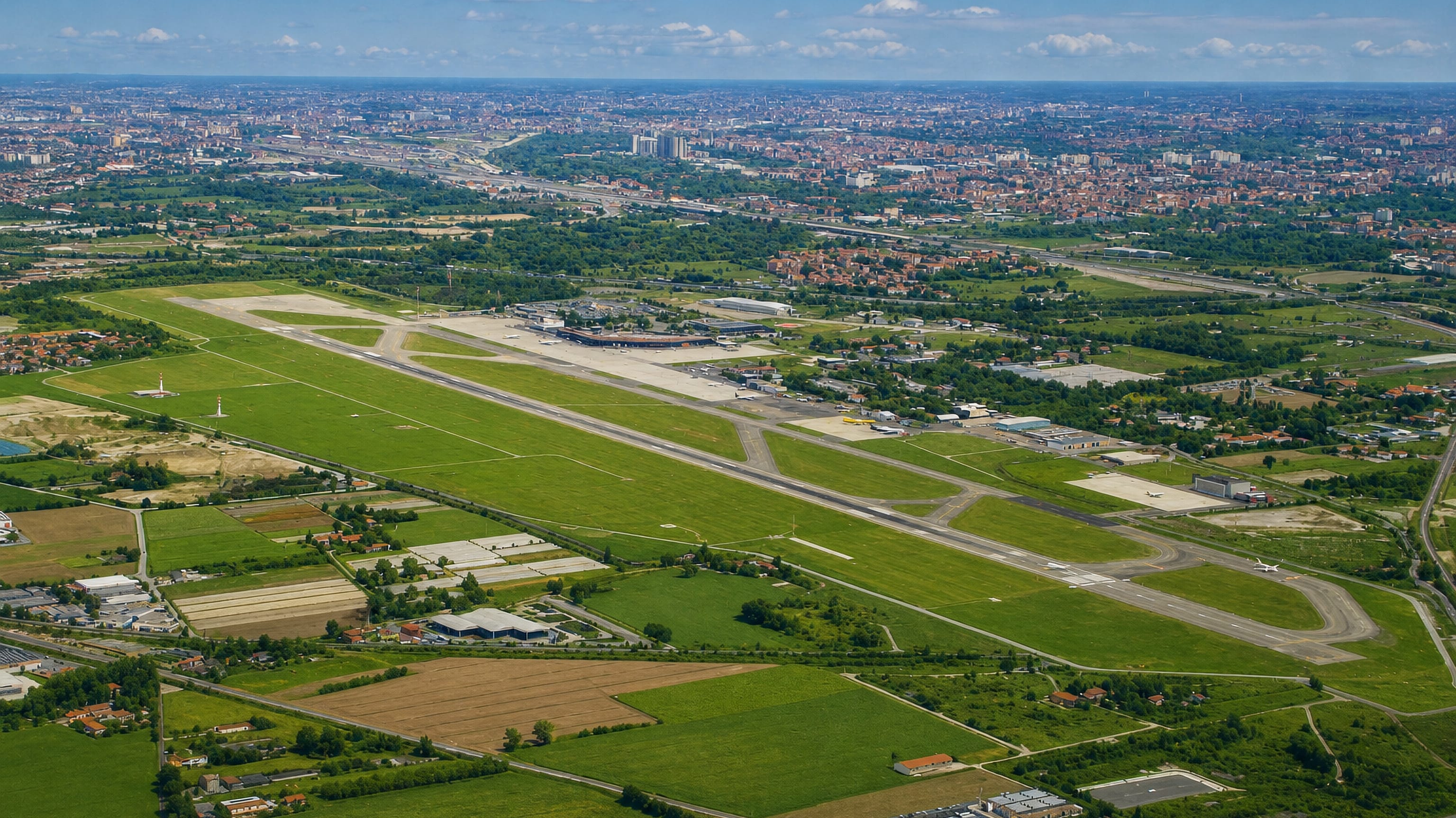 Aerial of Bologna's Marconi Airport runway in Borgo Panigale, with the city stretching to the horizon